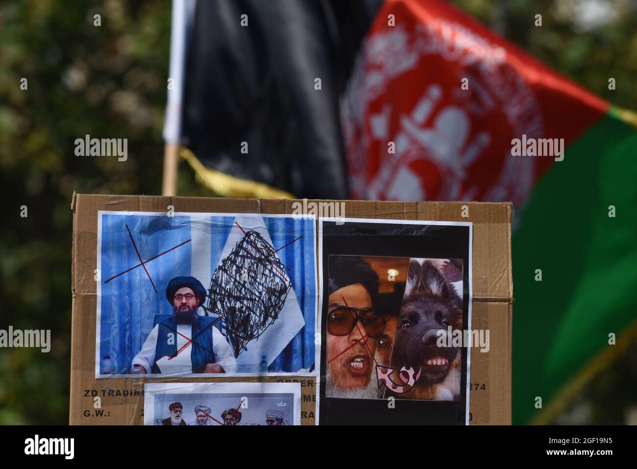 *** STRICTEMENT AUCUNE VENTE AUX MÉDIAS OU ÉDITEURS FRANÇAIS - DROITS RÉSERVÉS ***22 AOÛT 2021 - PARIS, FRANCE: Des centaines d'Afghans et de Français se réunissent sur la place de la République pour protester contre la prise de pouvoir par les talibans de l'Afghanistan et exiger une évacuation sûre des Afghans et de leur famille depuis l'aéroport de Kaboul. Ce manifestant détient un écriteau contre le mollah Abdul Ghani Baradar, l'un des plus hauts responsables talibans. Le drapeau afghan est visible en arrière-plan. Banque D'Images