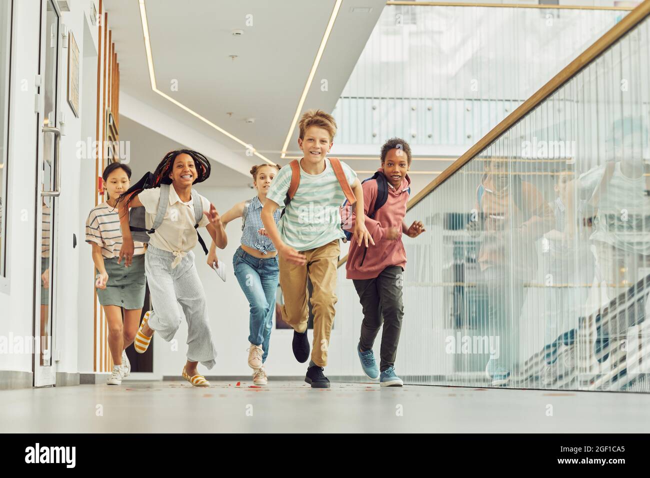 Portrait complet d'un groupe multiethnique d'écoliers qui se dirige vers l'appareil photo à l'intérieur et souriant heureux, espace de copie Banque D'Images