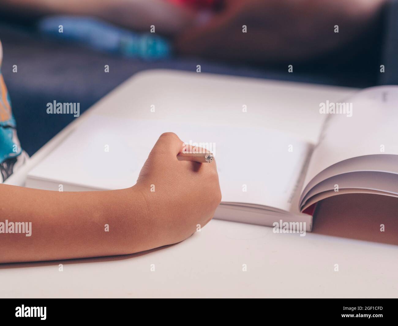 Gros plan d'un enfant avec un livre et un crayon dans sa main. Concept d'éducation de la petite enfance, de retour à l'école Banque D'Images