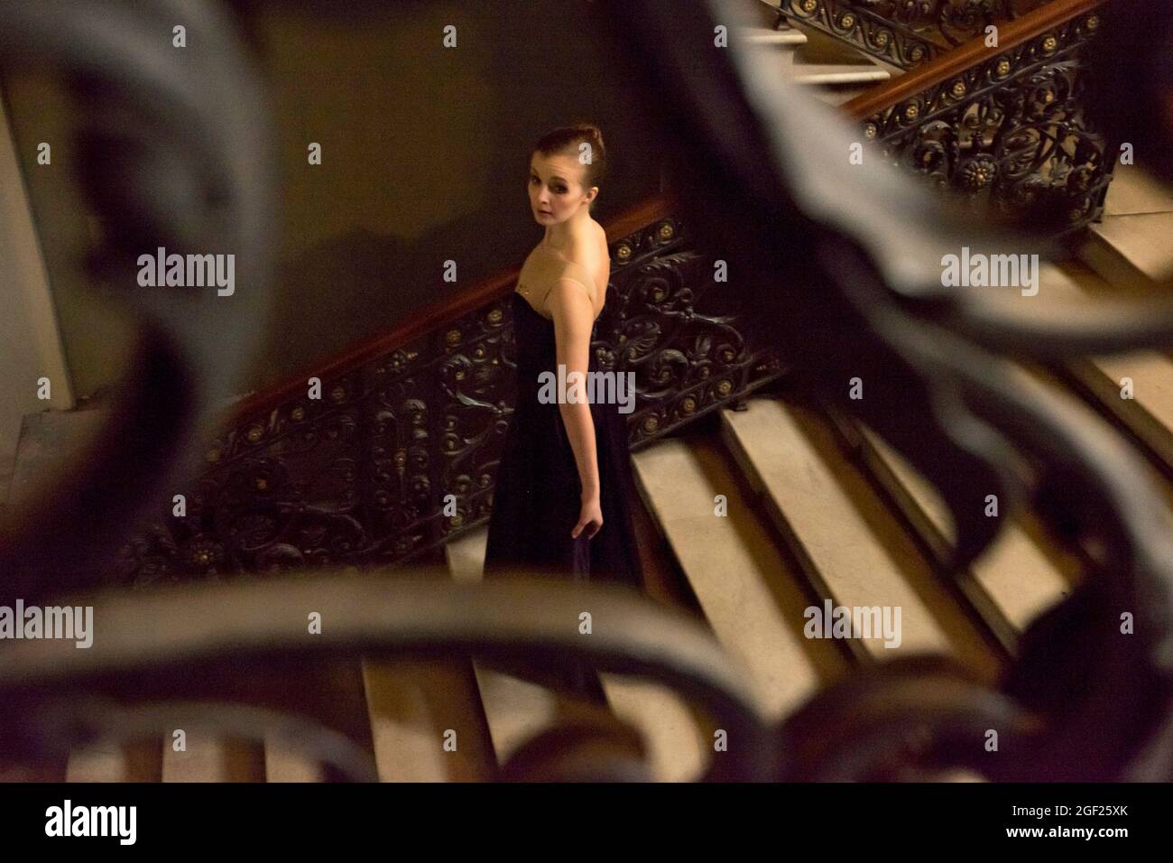 Une belle jeune femme vêtue d'une élégante robe descend un escalier élaboré dans un ancien palais russe de Saint-Pétersbourg Banque D'Images