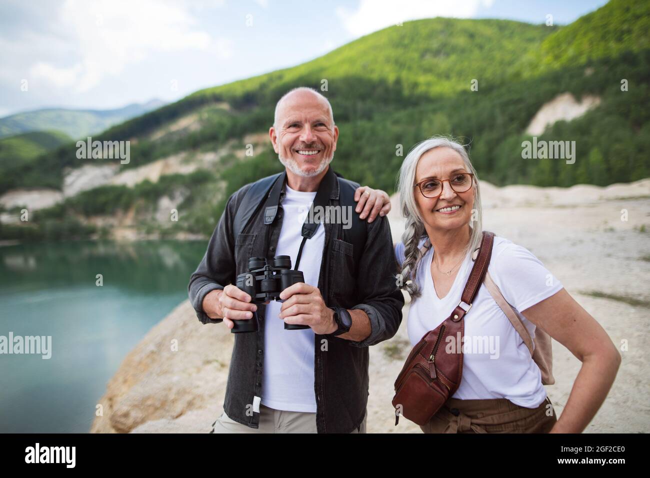 Joyeux couple senior sur une randonnée les vacances d'été, en utilisant des jumelles. Banque D'Images