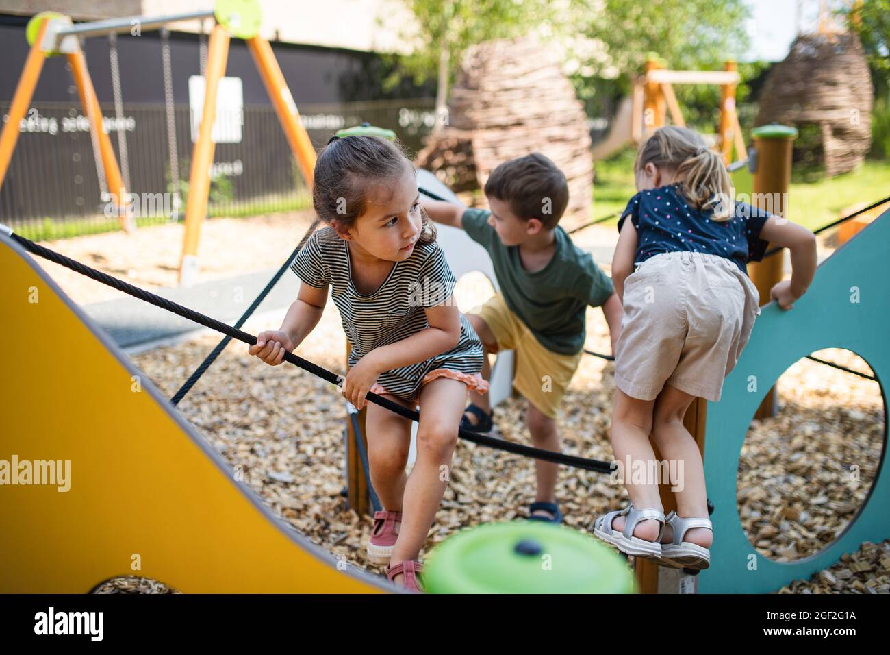 Groupe de jeunes enfants de la maternelle jouant à l'extérieur sur le terrain de jeu. Banque D'Images