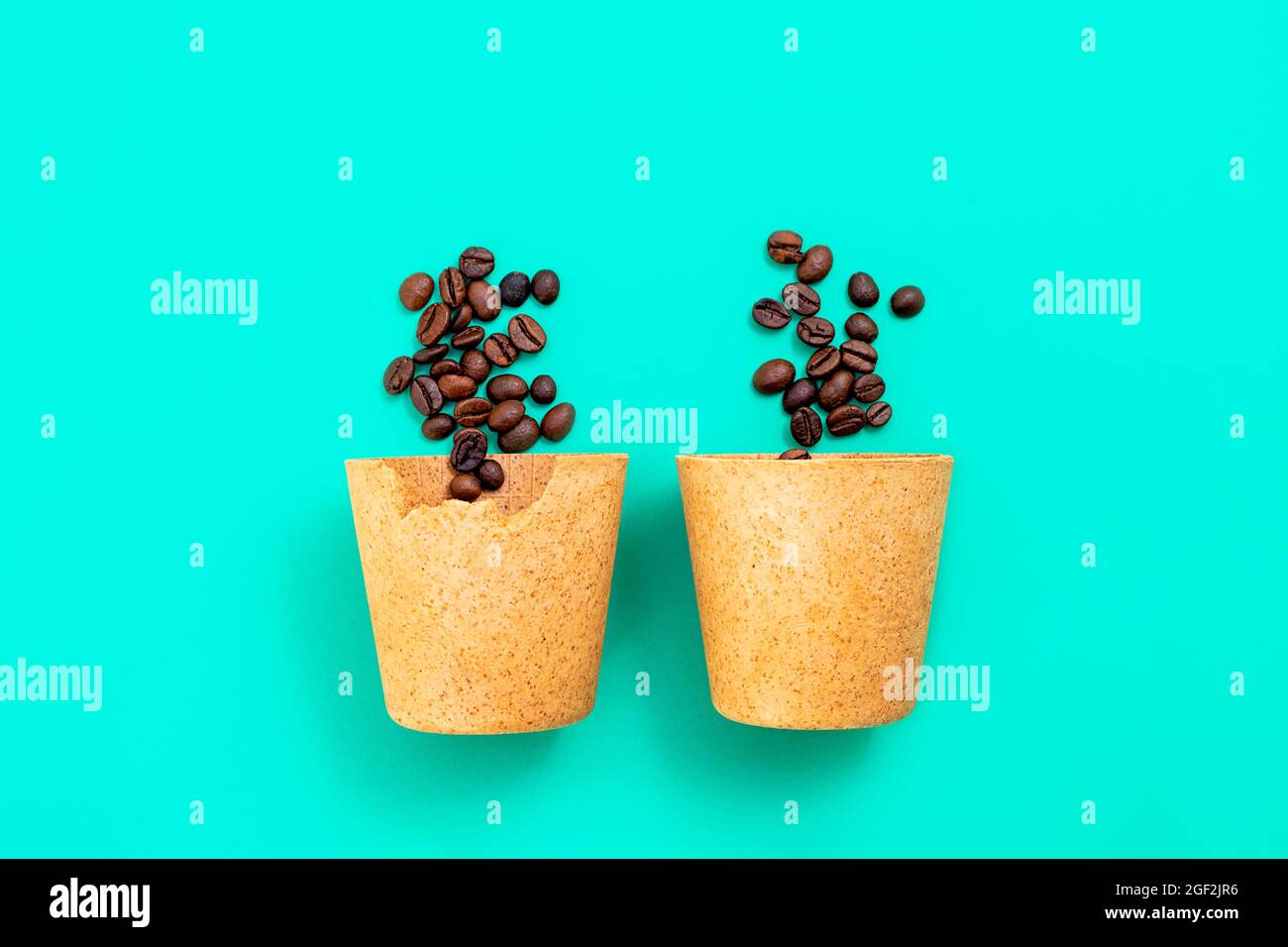 Deux tasses de café écologique comestibles que vous pouvez manger après avoir bu, faites à partir de gaufres, avec des grains de café sur fond vert. Concept zéro déchet, pose à plat Banque D'Images