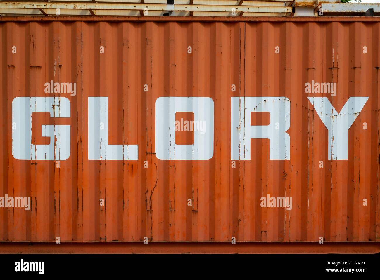 Le mot Glory écrit sur un conteneur industriel en émail blanc sur fond orange Banque D'Images