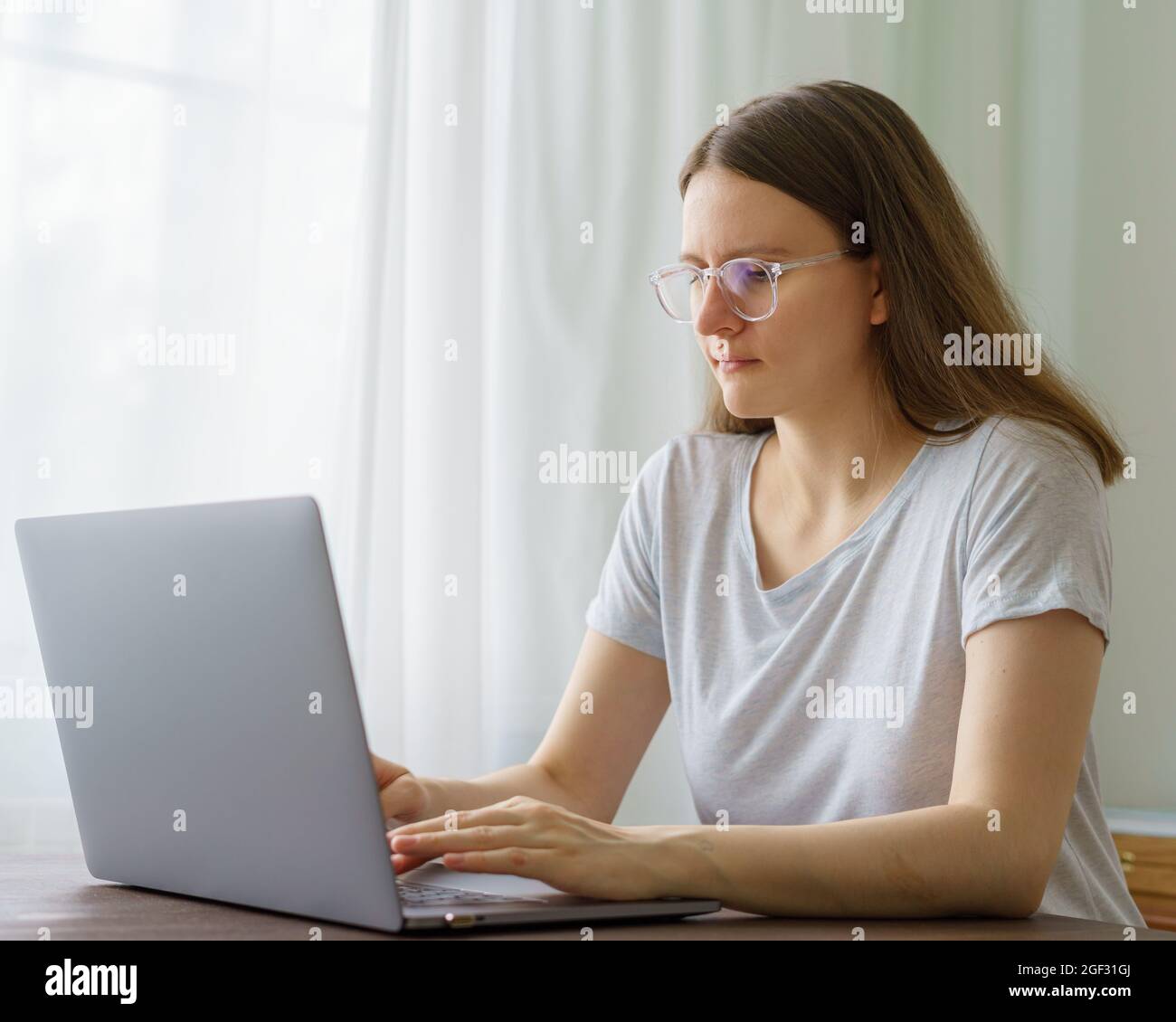 Femme millénaire en dactylographie verglaheuse sur ordinateur portable. Étudiant participant à des cours en ligne à domicile Banque D'Images