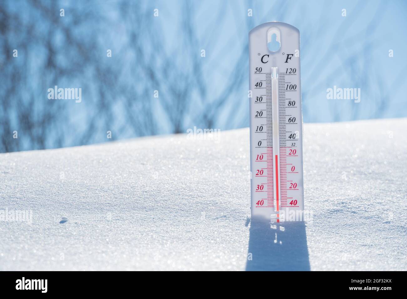 Le thermomètre se trouve sur la neige et affiche un négatif Température par temps froid sur le ciel bleu. Conditions météorologiques avec air faible et température ambiante t Banque D'Images