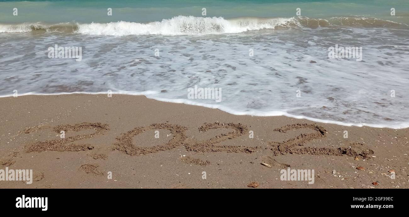 Bonne année 2022, lettrage sur la plage avec vague et bleu clair de mer.  Chiffres 2022 ans sur la mer, message manuscrit dans le sable doré Photo  Stock - Alamy