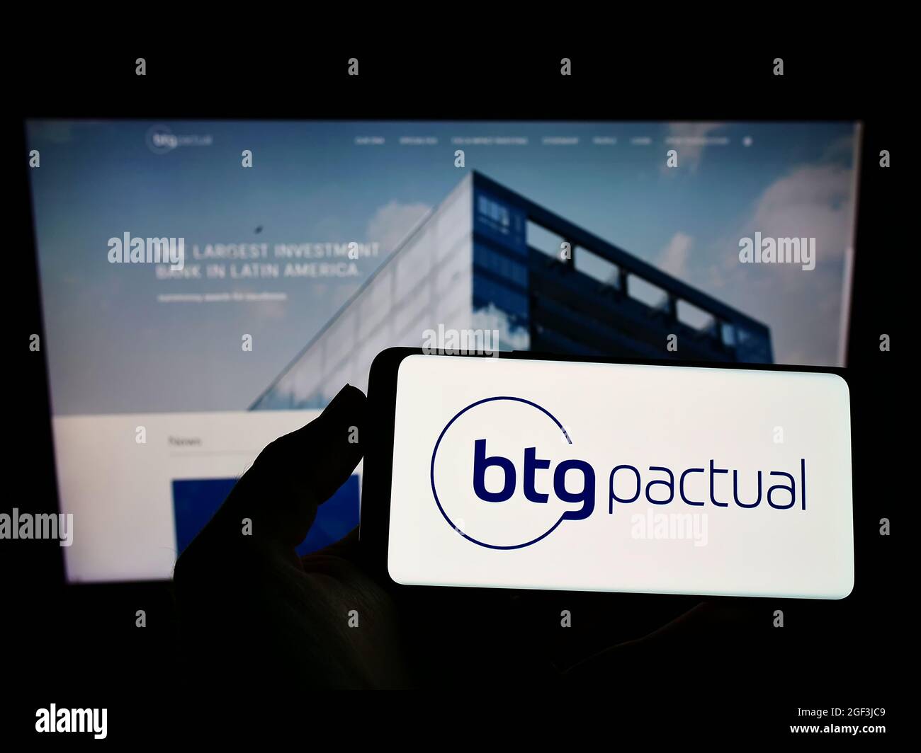 Personne détenant un smartphone avec le logo de la société financière brésilienne BTG Penal S.A. à l'écran devant le site Web. Mise au point sur l'affichage du téléphone. Banque D'Images