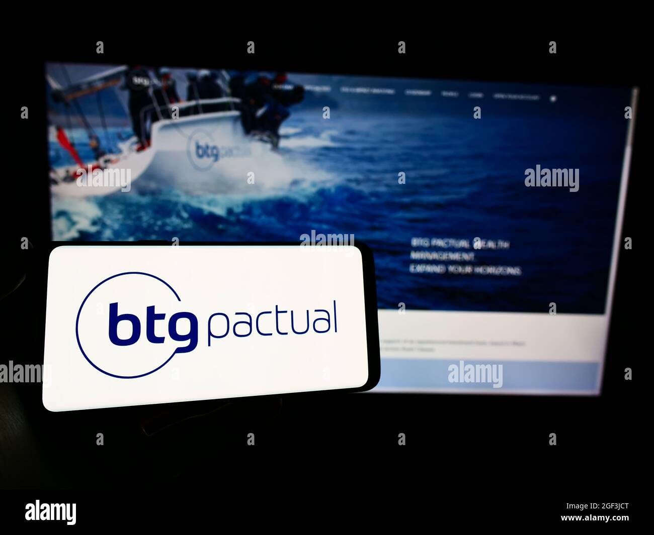 Personne tenant un téléphone portable avec le logo de la société financière brésilienne BTG Pactual S.A. à l'écran en face de la page Web. Mise au point sur l'affichage du téléphone. Banque D'Images