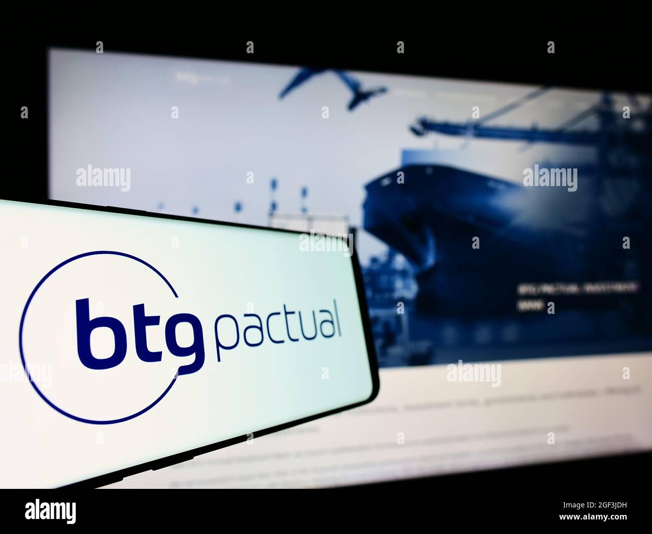 Téléphone mobile avec logo de la société financière brésilienne BTG Penactual sa à l'écran en face du site Web d'affaires. Mise au point au centre-gauche de l'écran du téléphone. Banque D'Images