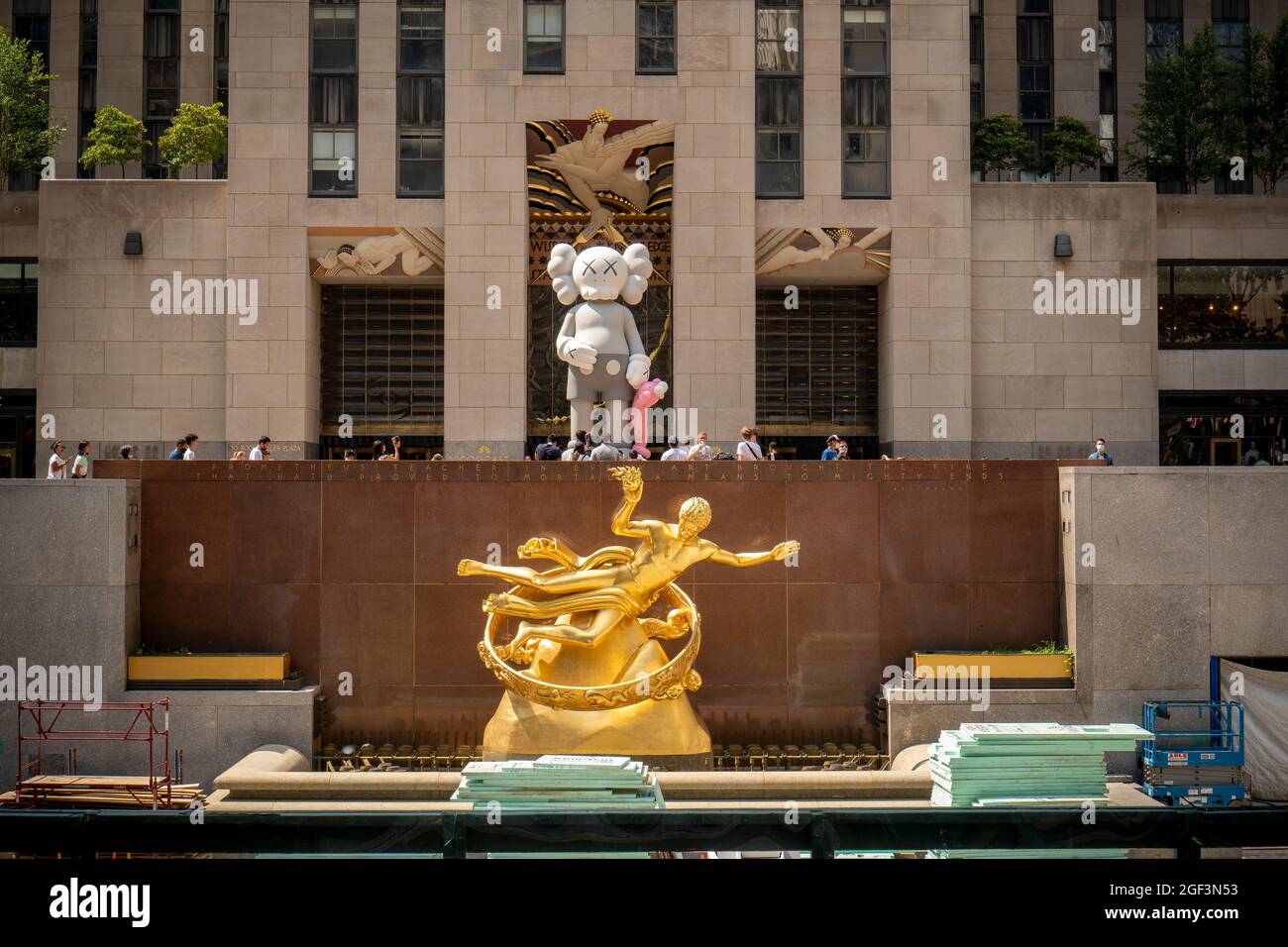 Les visiteurs de la Rockefeller Plaza voient "PARTAGER" par l'artiste KAWS exposé dans le cadre de l'art public du Rockefeller Center, vu au-dessus de "Prométhée" de Paul Manship, le mercredi 11 août 2021. La sculpture en bronze de 18 pieds de haut, présentant des motifs de personnages de dessins animés utilisés par l'artiste, sera exposée jusqu'en octobre. (© Richard B. Levine) Banque D'Images