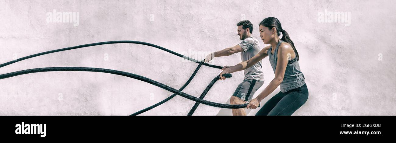 Gym personnes entraînement corde de bataille exercice panorama. Fitness Gym FIT couple s'entraîner avec des cordes de combat. Femme et homme s'entraîner ensemble Banque D'Images