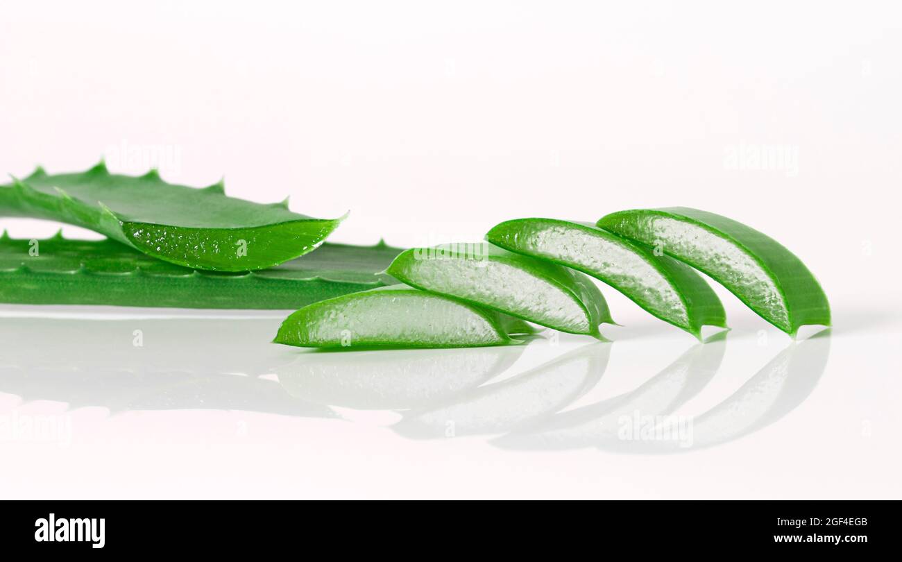 feuilles vertes fraîches et tranches d'aloe vera sur fond blanc avec réflexion Banque D'Images