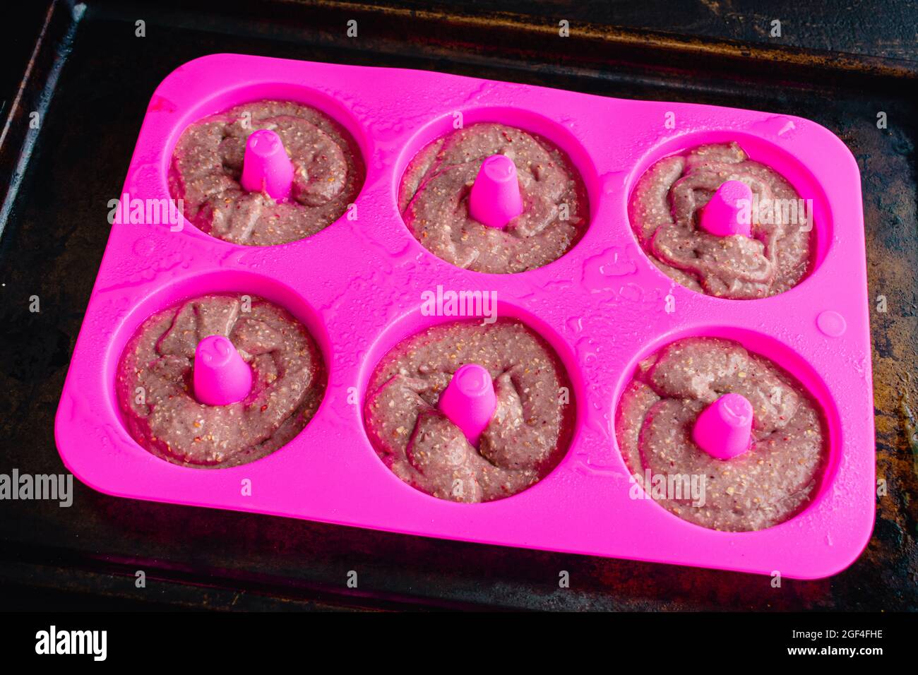 Pâte de beignet de framboise dans un moule de beignet cuit au silicone : pâte crue dans un moule de cuisson de beignet de silicone graissé Banque D'Images