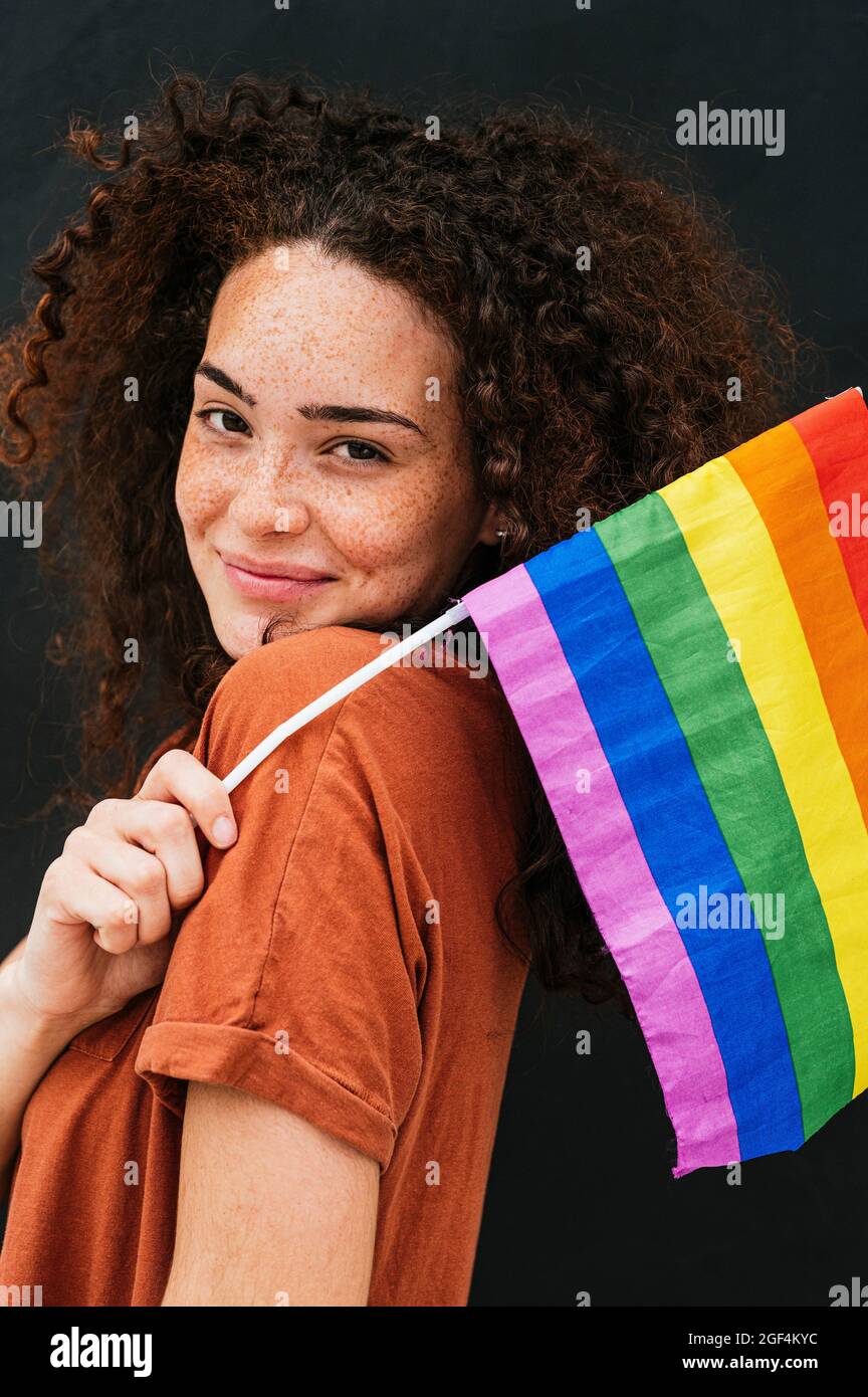 Belle jeune femme souriante portant un drapeau arc-en-ciel Banque D'Images