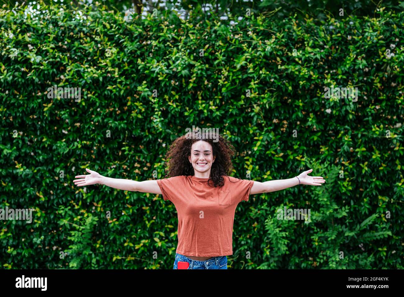 Bonne jeune femme aux bras étirés devant des plantes de lierre verte Banque D'Images