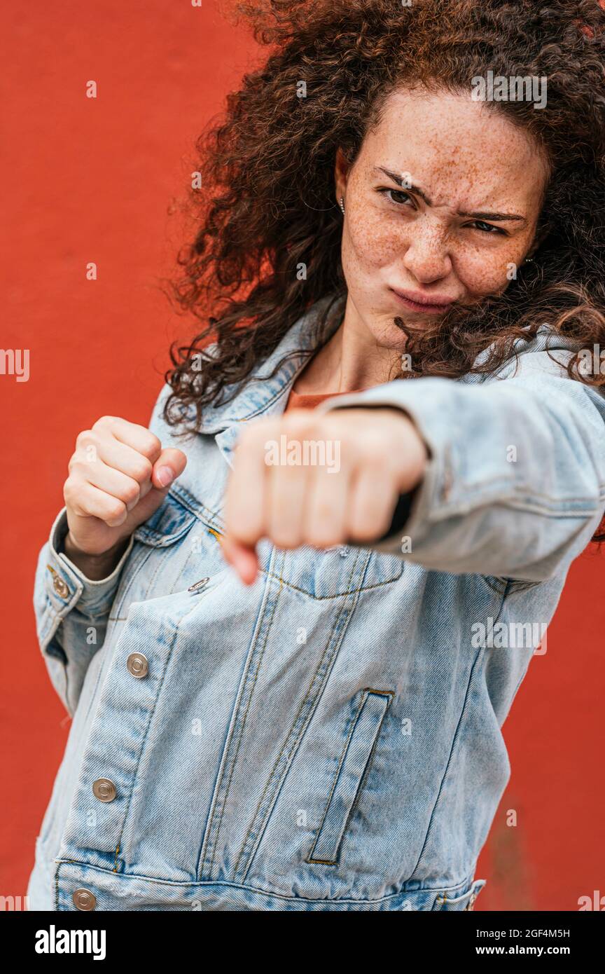 Jeune femme pointant avec poing tout en faisant le visage Banque D'Images Jeune femme pointant avec poing tout en faisant le visage Banque D'Images