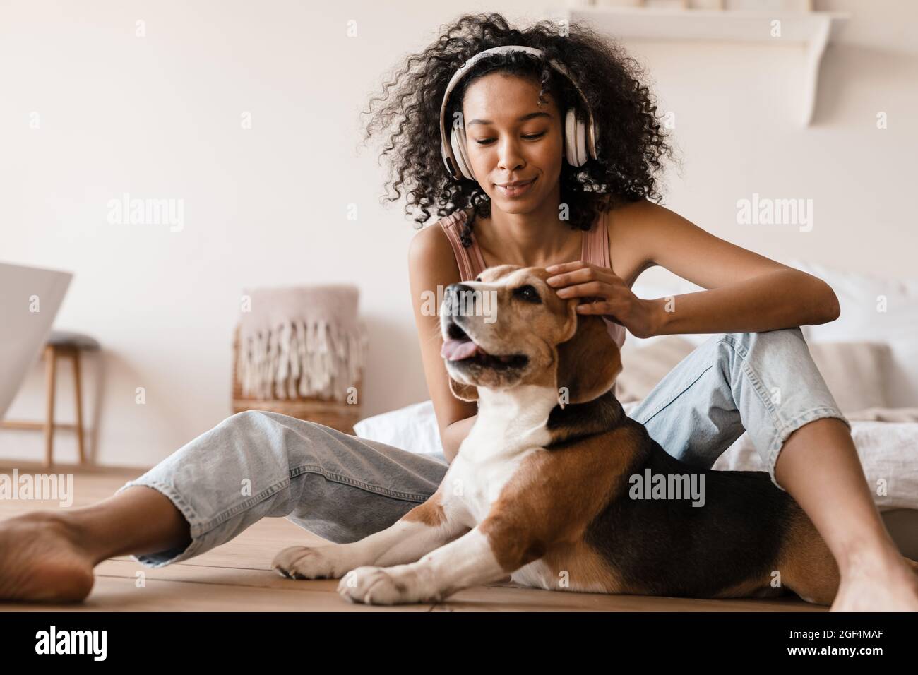 Jeune femme africaine en tenue decontractee avec un chiot beagle a la maison assis sur un sol jouant avec le chien Photo Stock Alamy