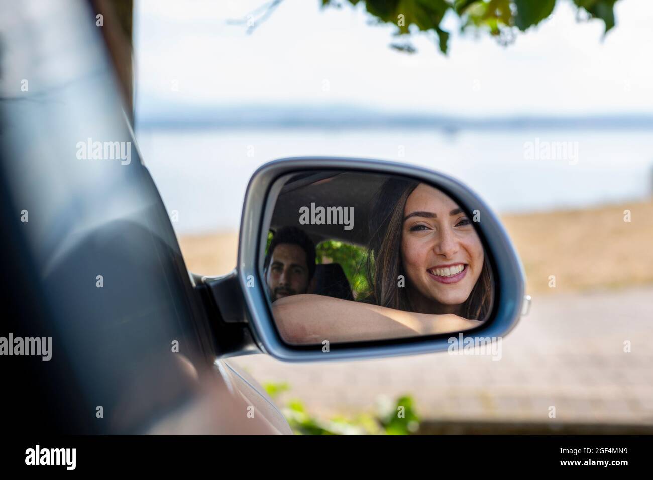 Reflet d'un couple souriant sur le rétroviseur latéral Banque D'Images