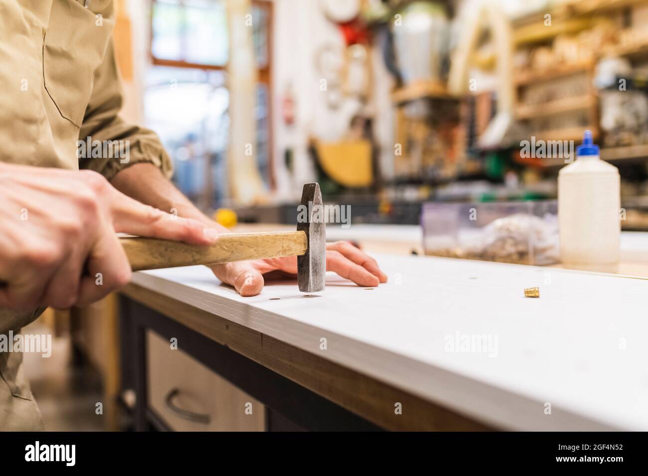 Un charpentier mâle mûr martèle en travaillant en atelier Banque D'Images