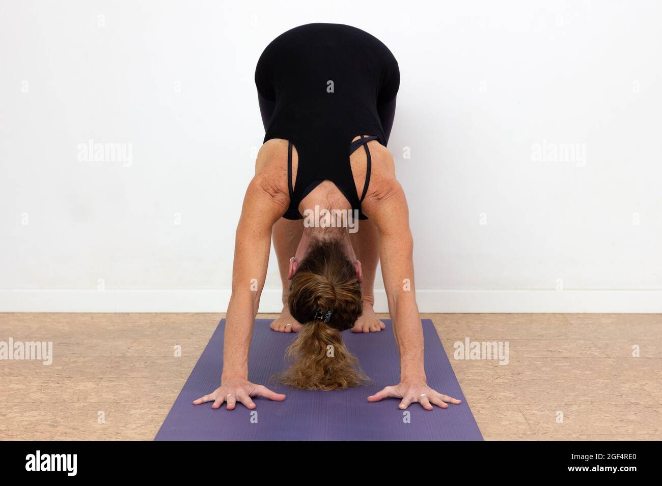 La femme pratique adho mukha svanasana yoga pose sur fond blanc. Yogi femelle dans l'asana de chien orienté vers le bas. Entraînement, concepts de fitness Banque D'Images