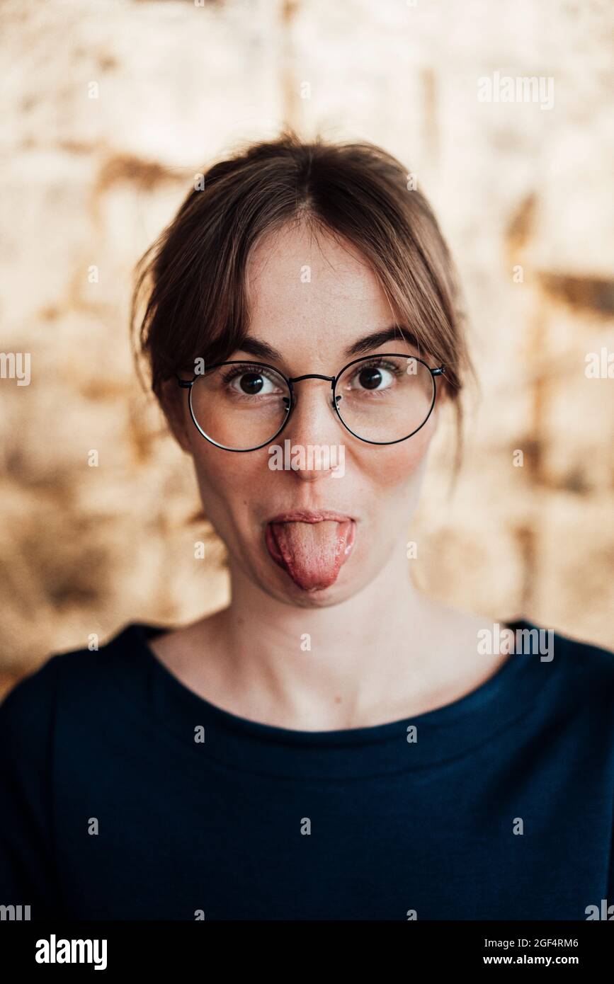 Jeune femme portant des lunettes qui dépassent de la langue Banque D'Images