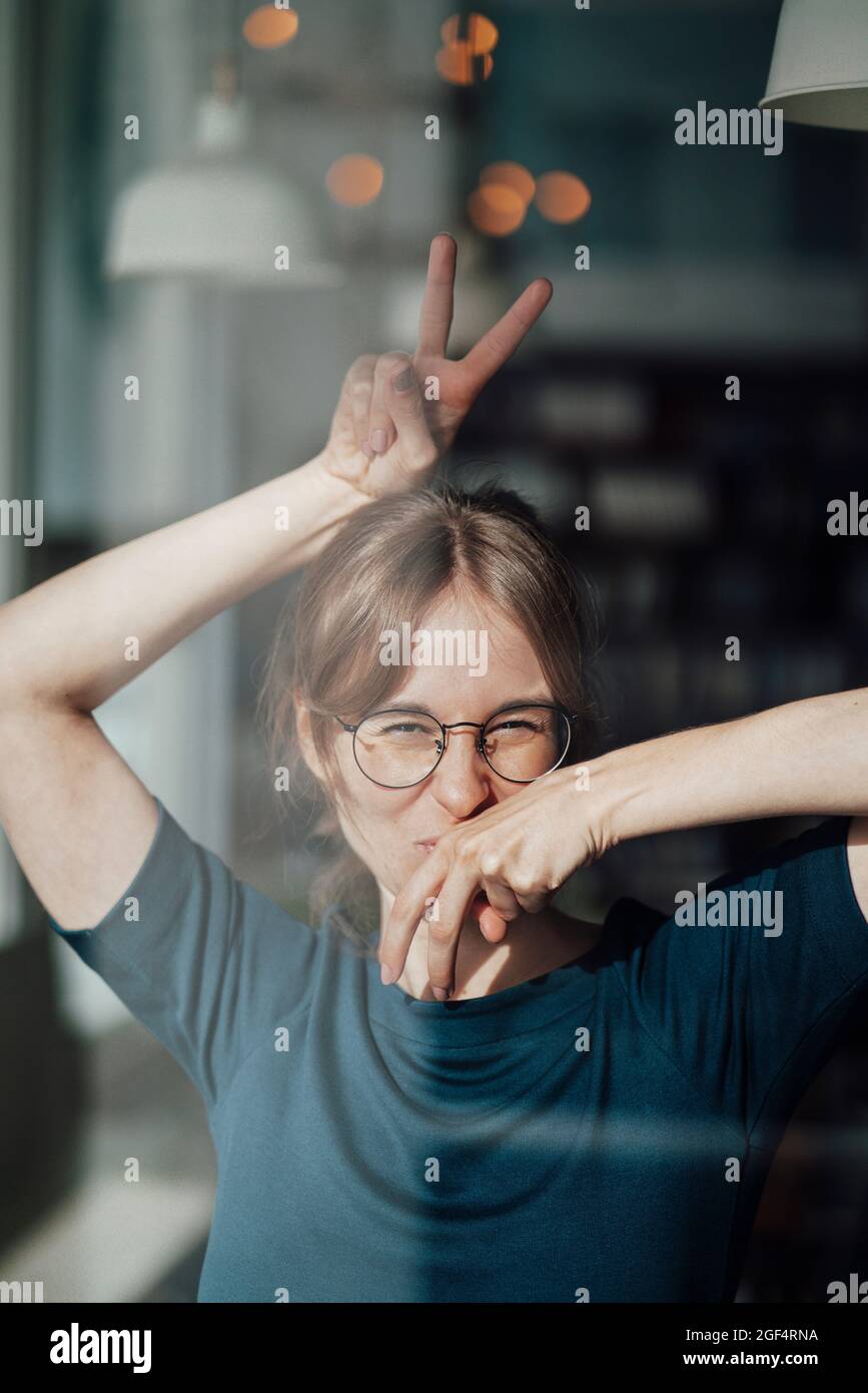 Jeune femme portant des lunettes gestante signe de paix Banque D'Images