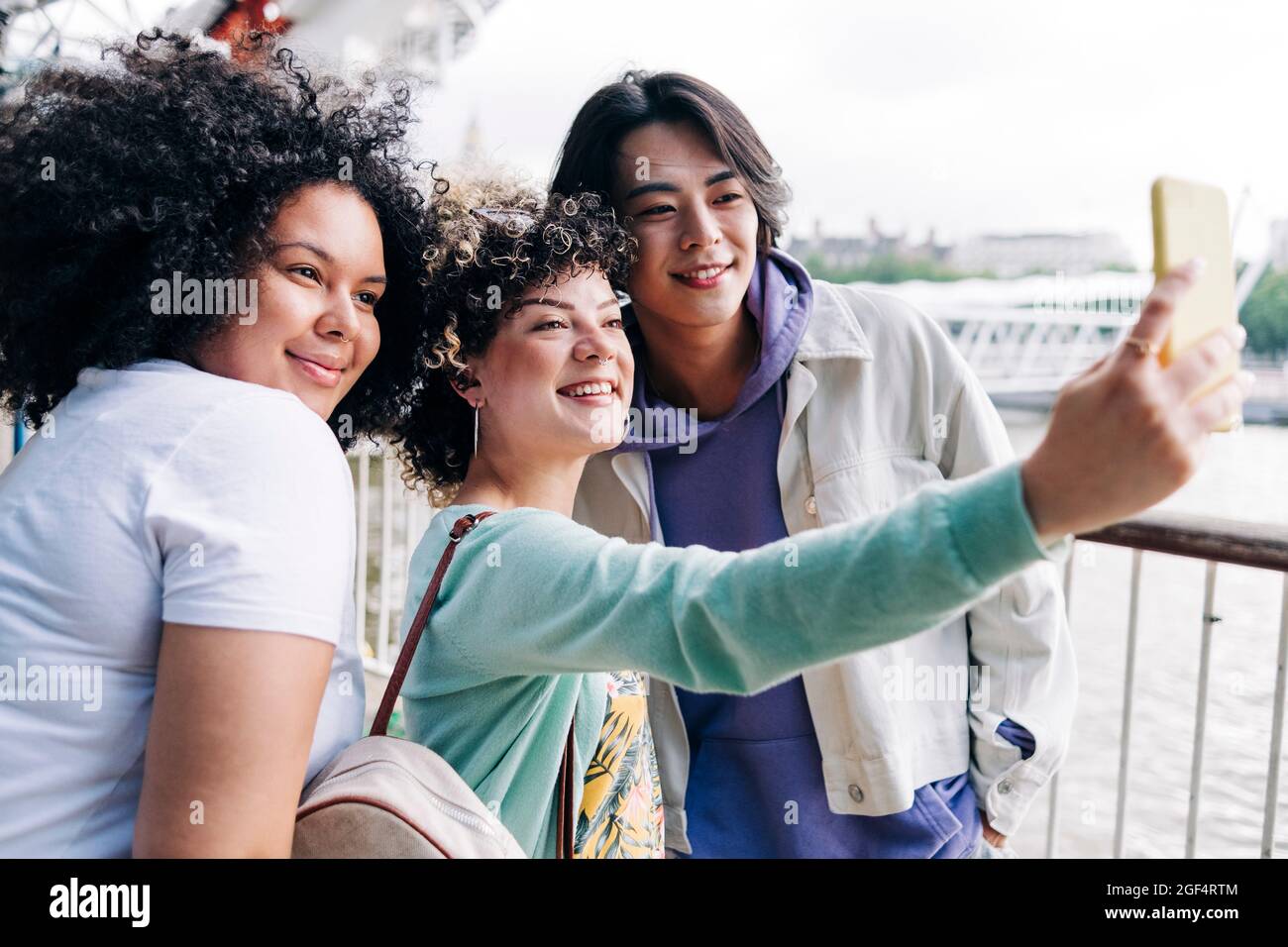 Femme souriante prenant le selfie avec des amis masculins et féminins Banque D'Images
