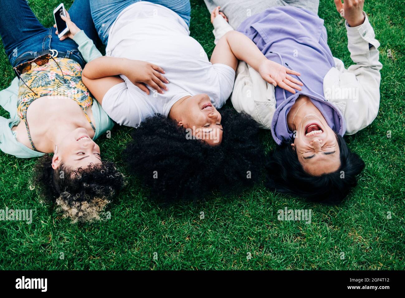 Heureux amis multiethniques hommes et femmes allongé sur l'herbe au parc Banque D'Images