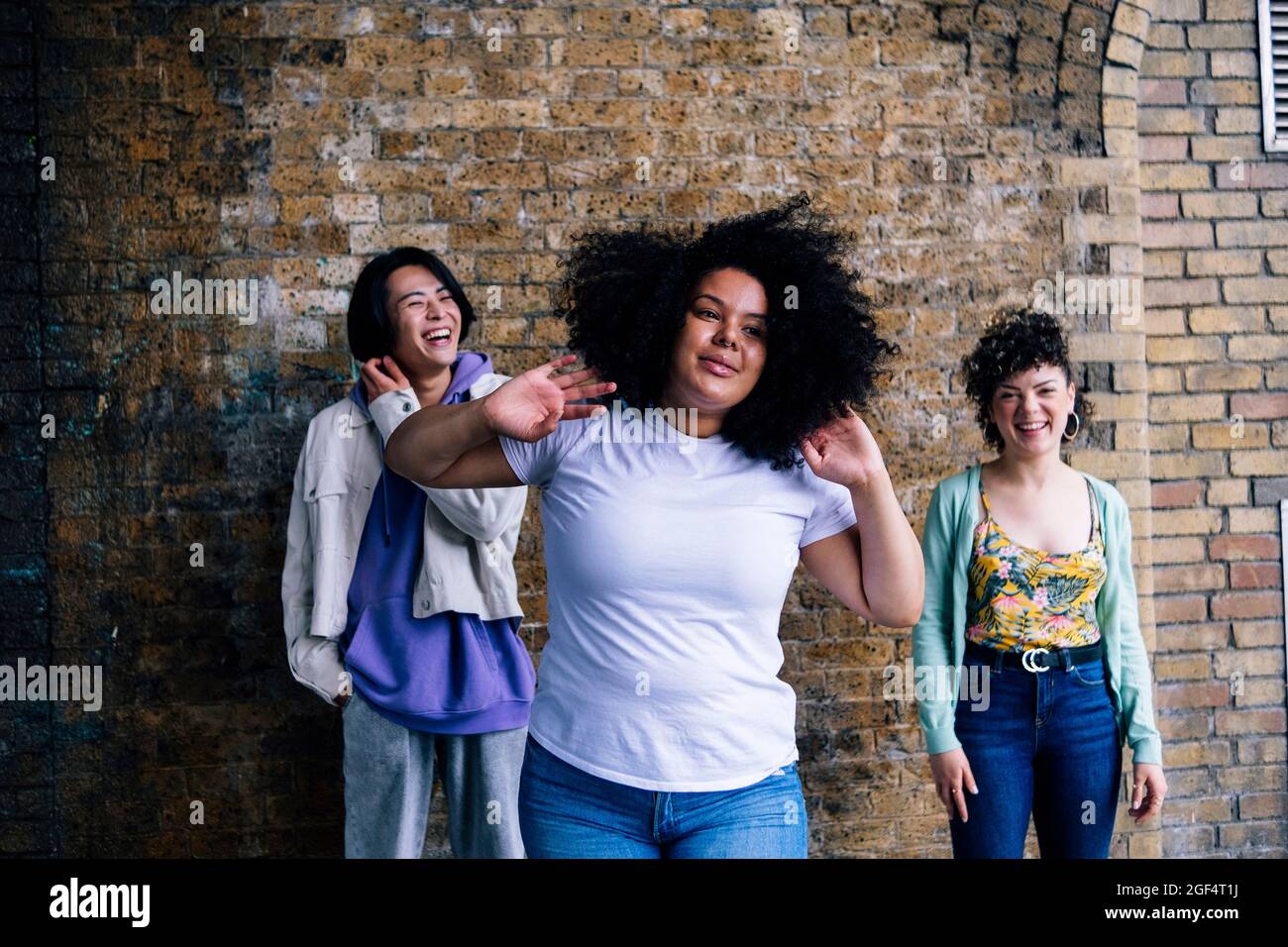 Jeune femme aux cheveux noirs bouclés debout devant des amis Banque D'Images
