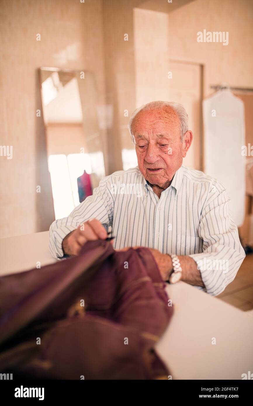Homme senior expert de la mode couture de tissu tout en travaillant avec une jeune femme collègue Banque D'Images