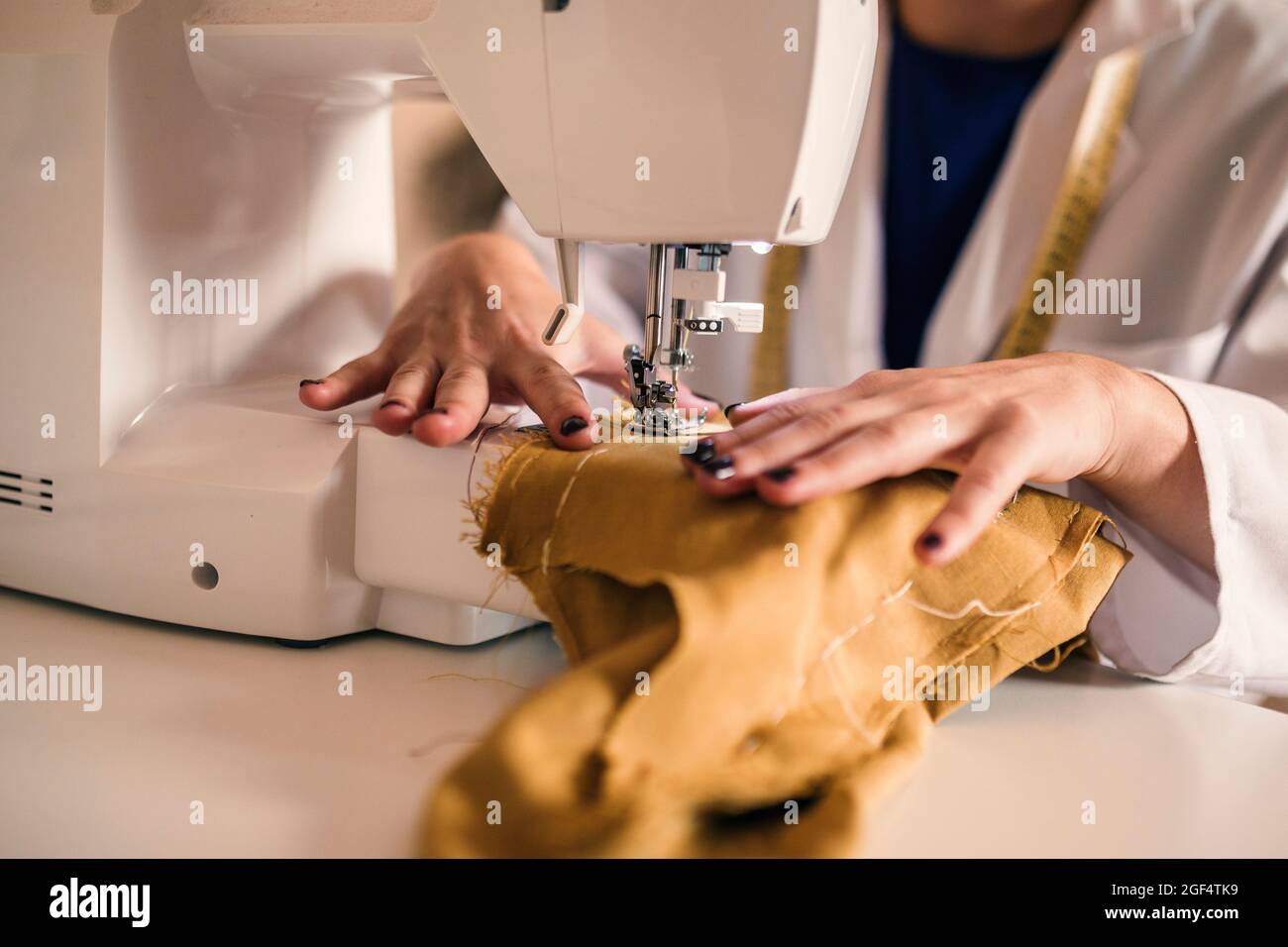 Jeune femme expert de la mode couture de tissu à travers la machine à l'atelier Banque D'Images