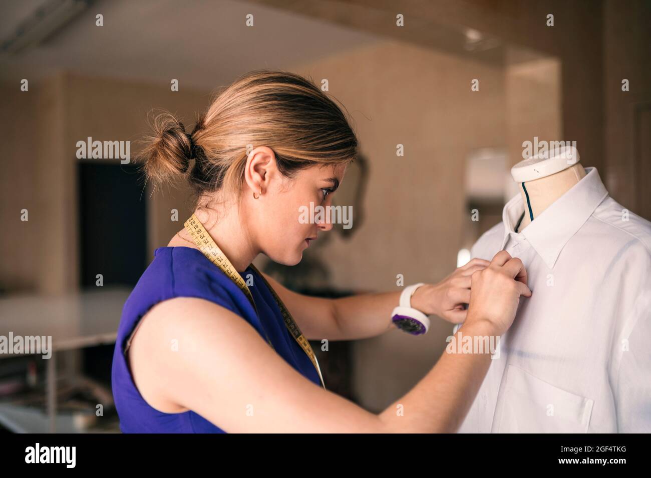 Jeune couturière couturière couture d'une chemise blanche sur mannequin à l'atelier Banque D'Images