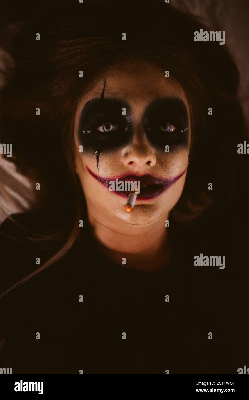 Femme avec maquillage cérémonial couché sur le lit à la maison pendant Halloween Banque D'Images