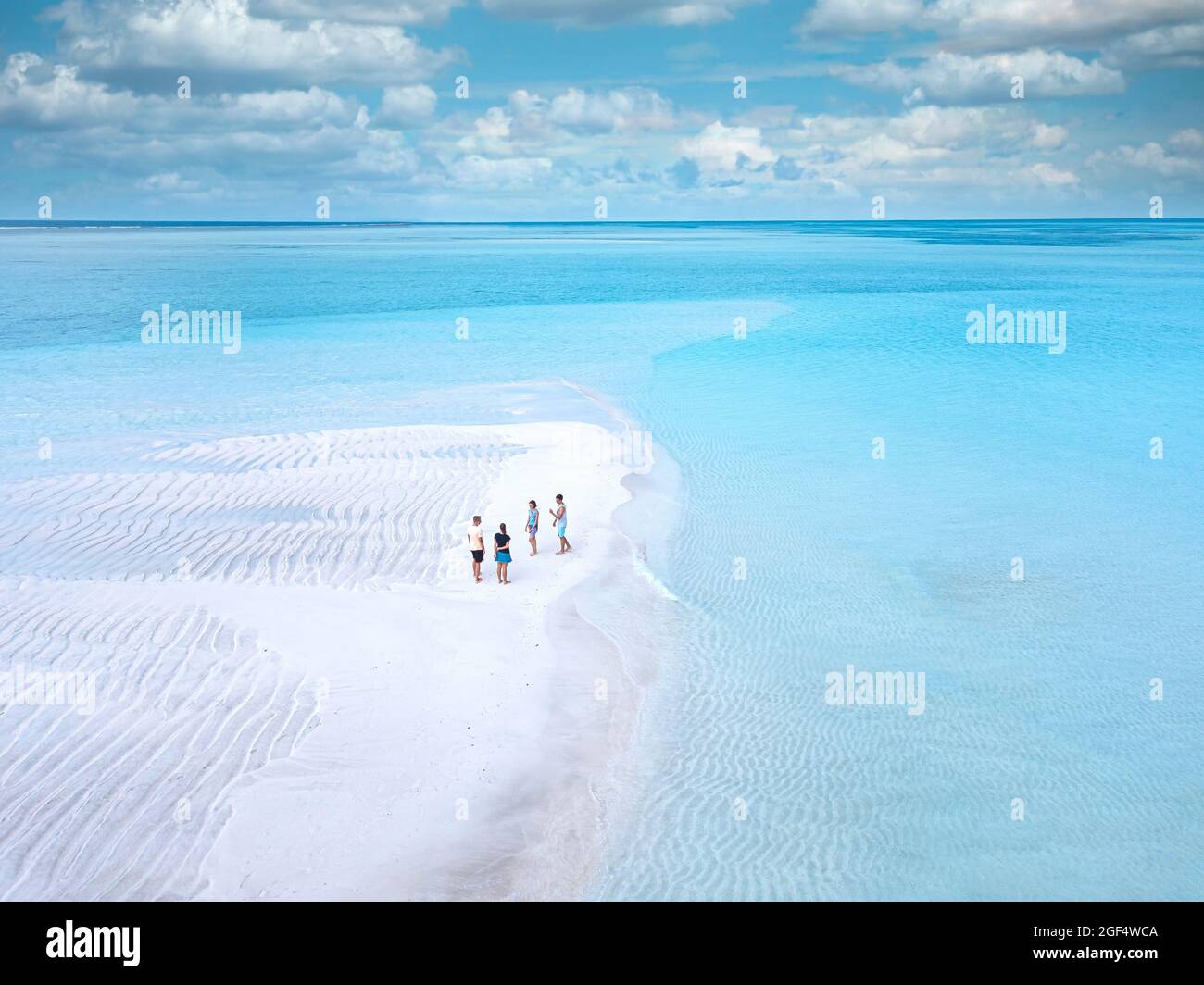 Vue aérienne de quatre personnes se tenant ensemble sur la plage côtière de sable de l'île de Thulusdhoo Banque D'Images