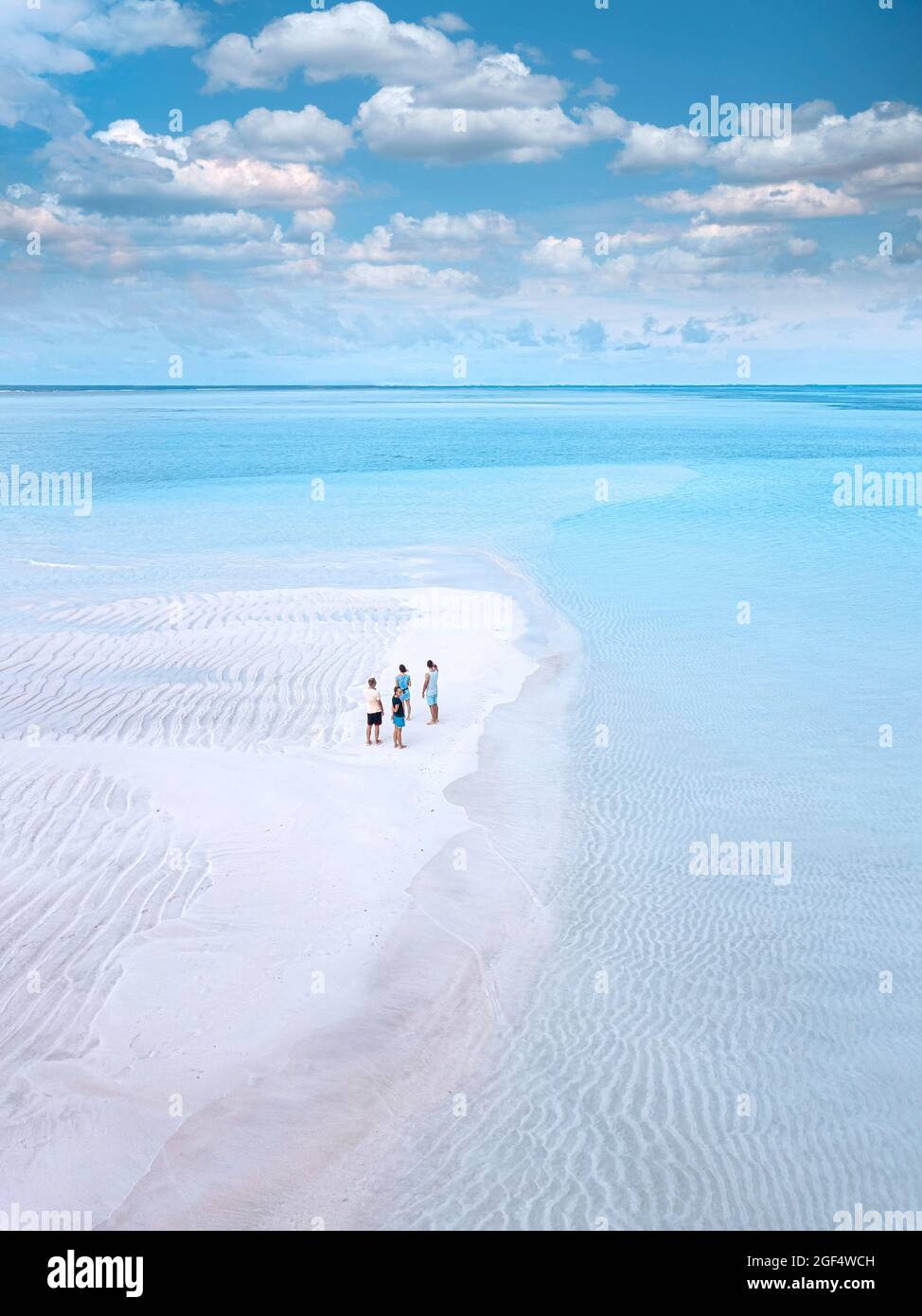Vue aérienne de quatre personnes se tenant ensemble sur la plage côtière de sable de l'île de Thulusdhoo Banque D'Images