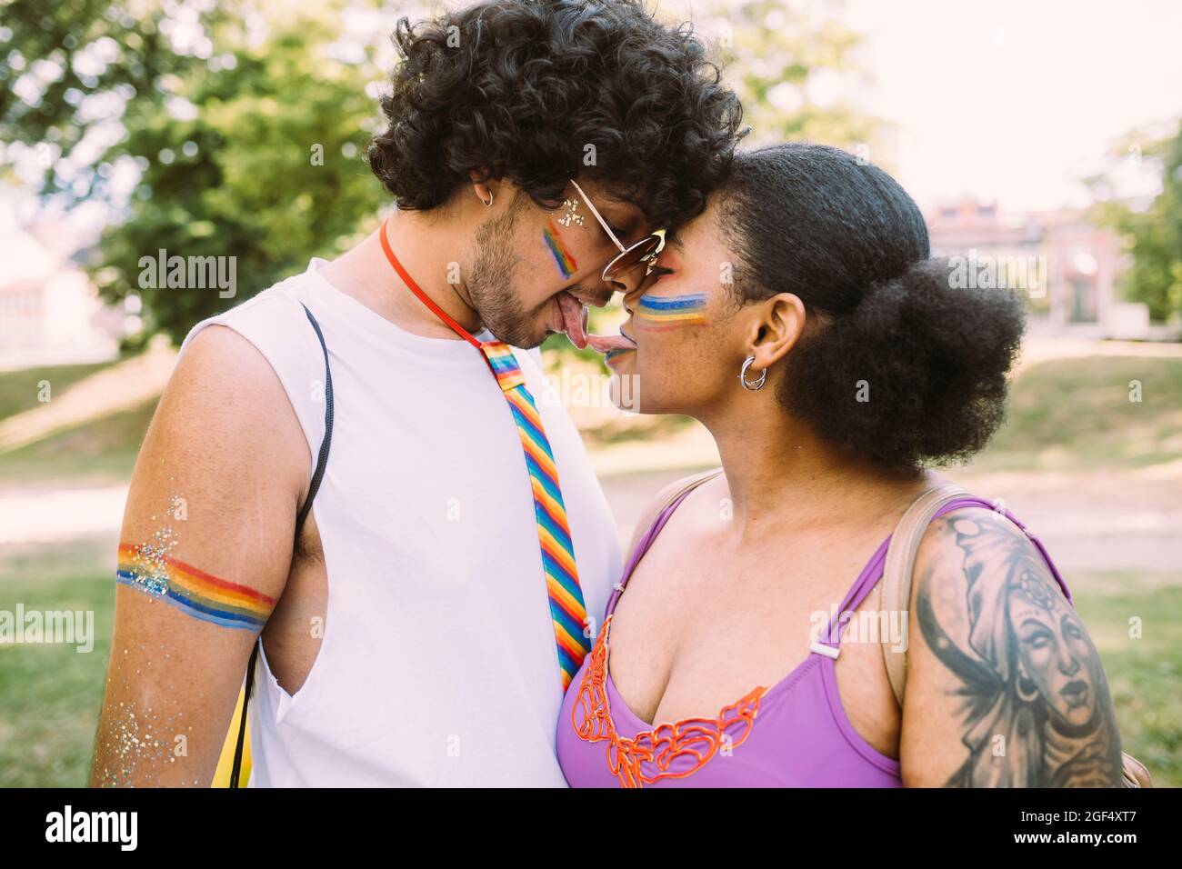 Jeune couple touching tongues in park Banque D'Images