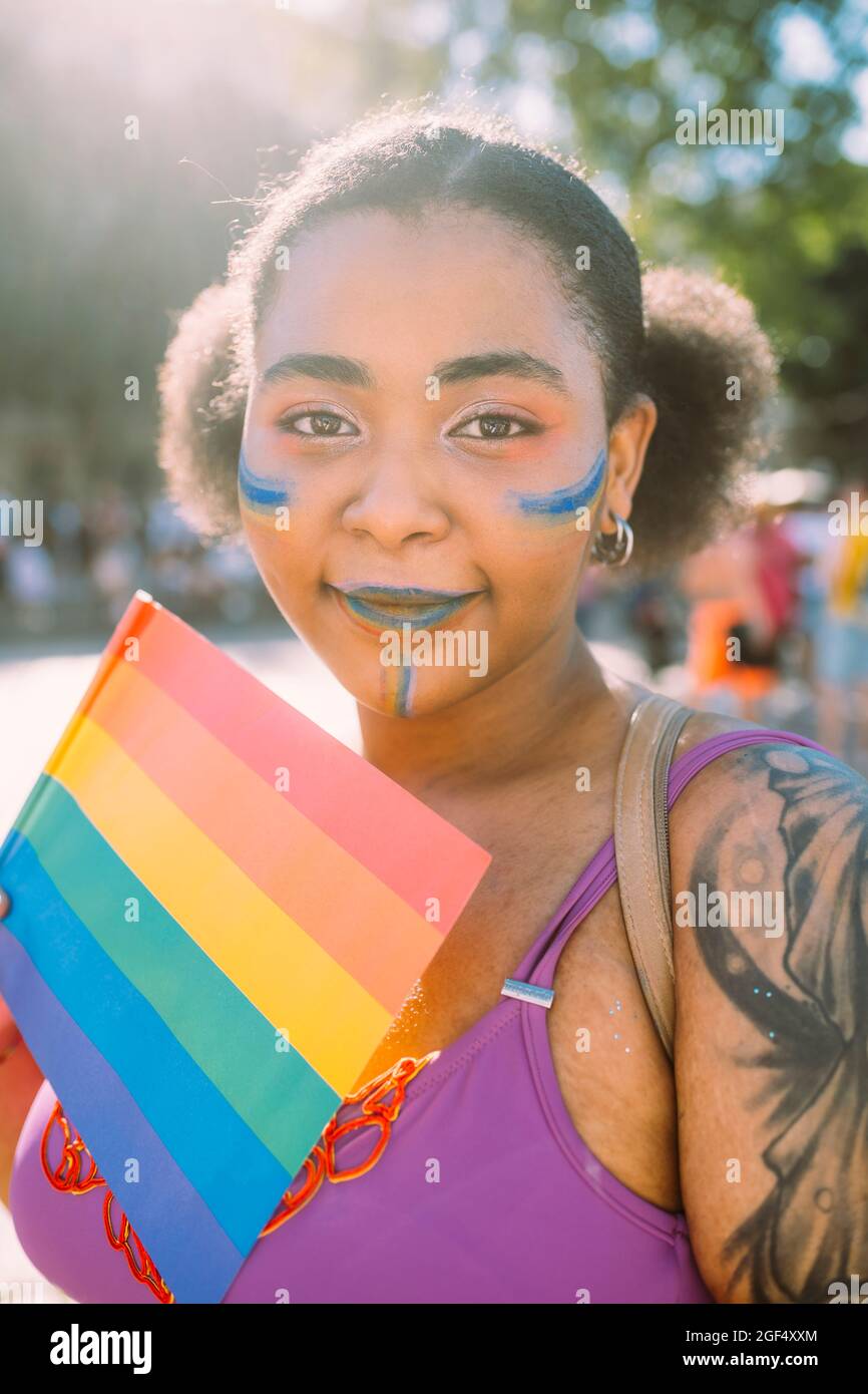 Jeune femme avec drapeau arc-en-ciel le jour ensoleillé Banque D'Images