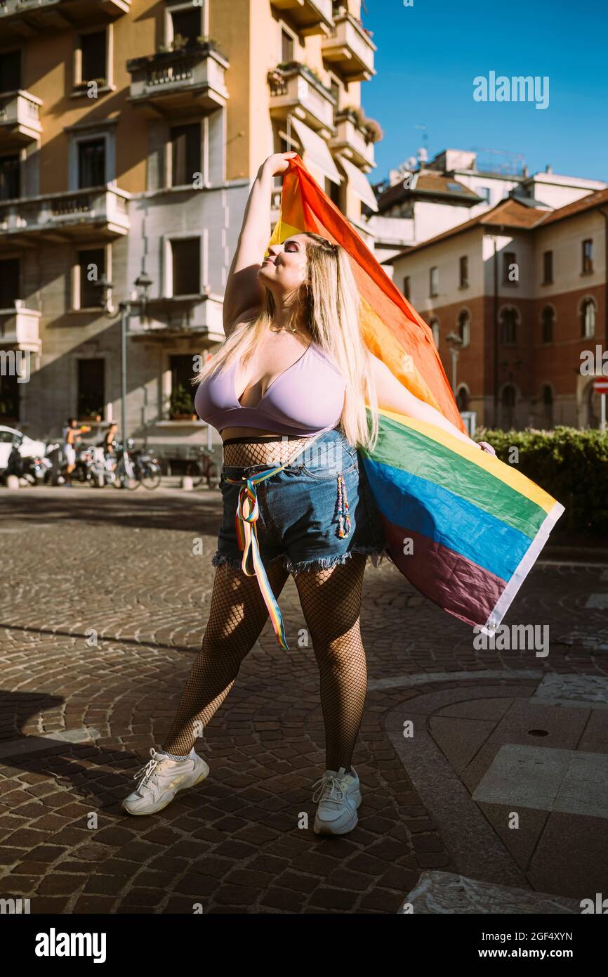 Manifestant féminin avec drapeau arc-en-ciel debout dans la rue Banque D'Images