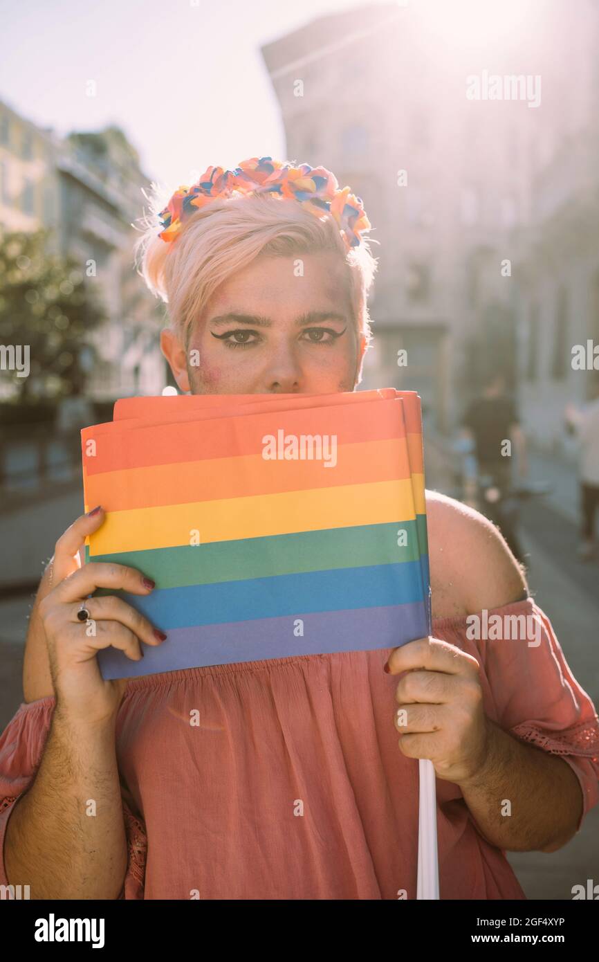 Activiste mâle couvrant la bouche avec un drapeau arc-en-ciel Banque D'Images