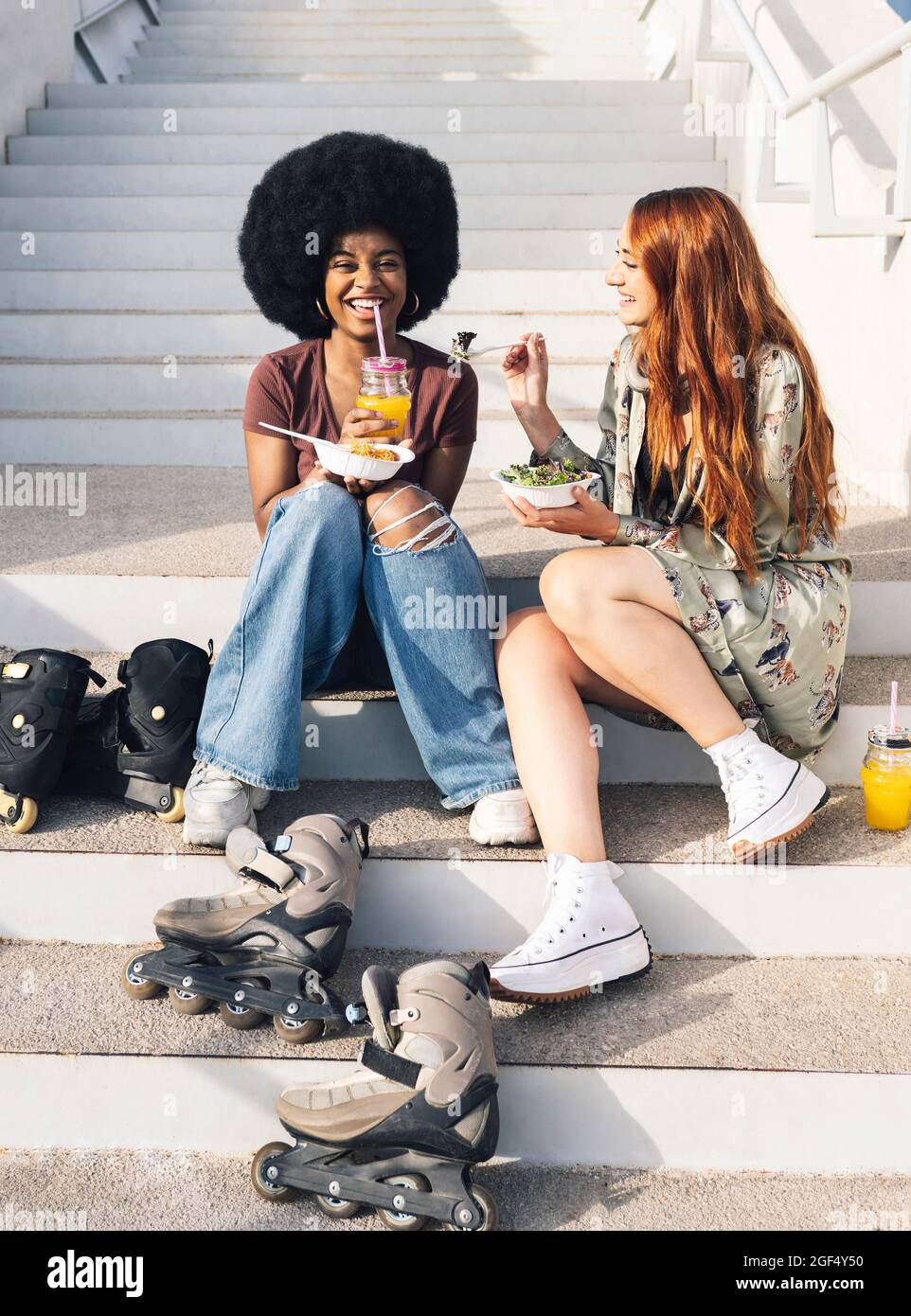 Des amies multi-ethniques gaies qui apprécient la nourriture et les boissons dans l'escalier Banque D'Images