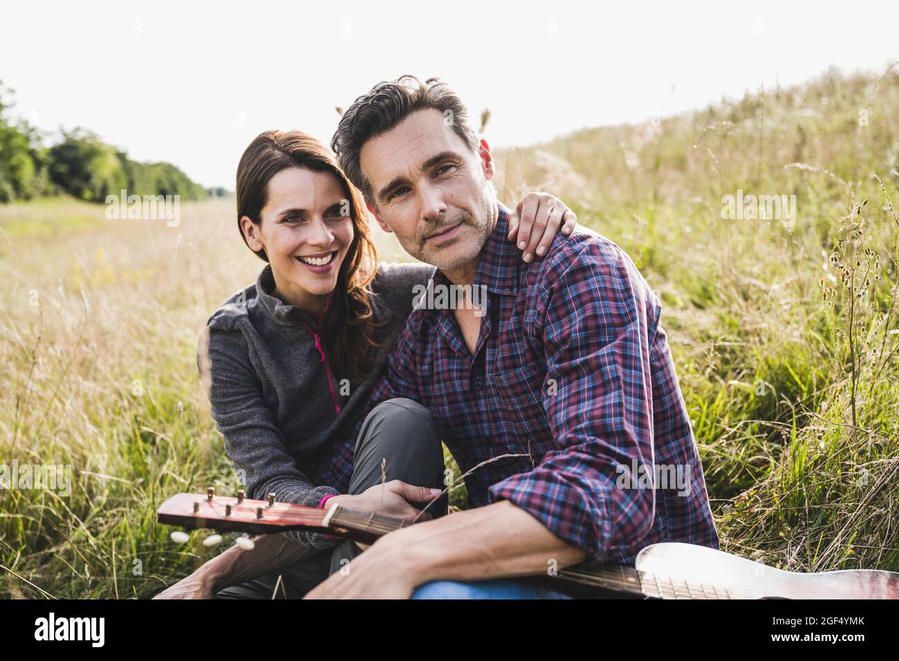 Randonneurs masculins et féminins assis avec guitare Banque D'Images
