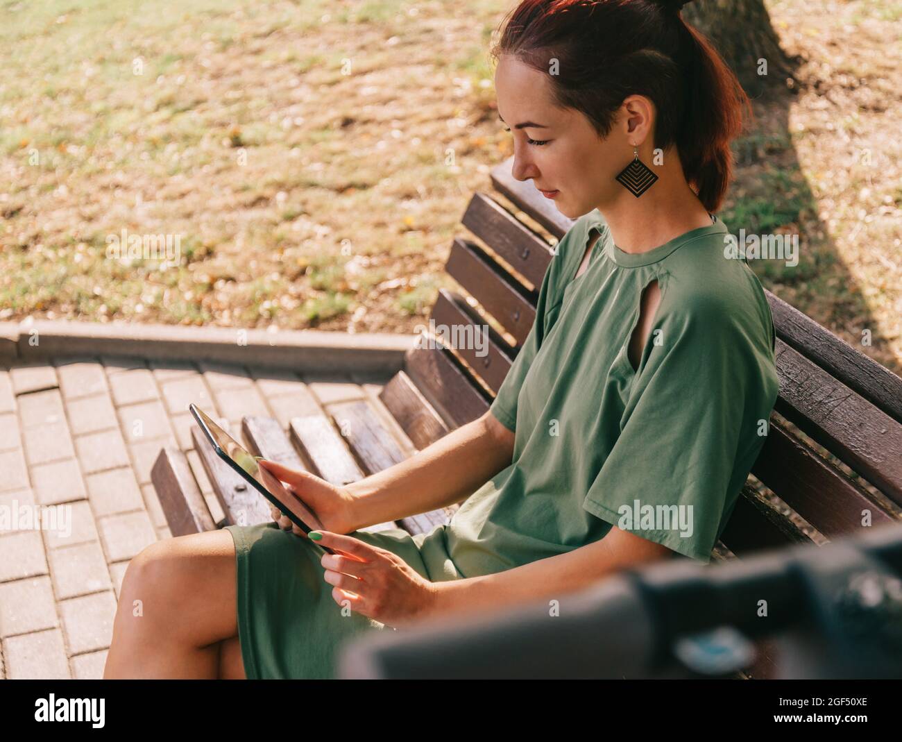 Jeune femme assise avec une tablette numérique sur un banc. Banque D'Images