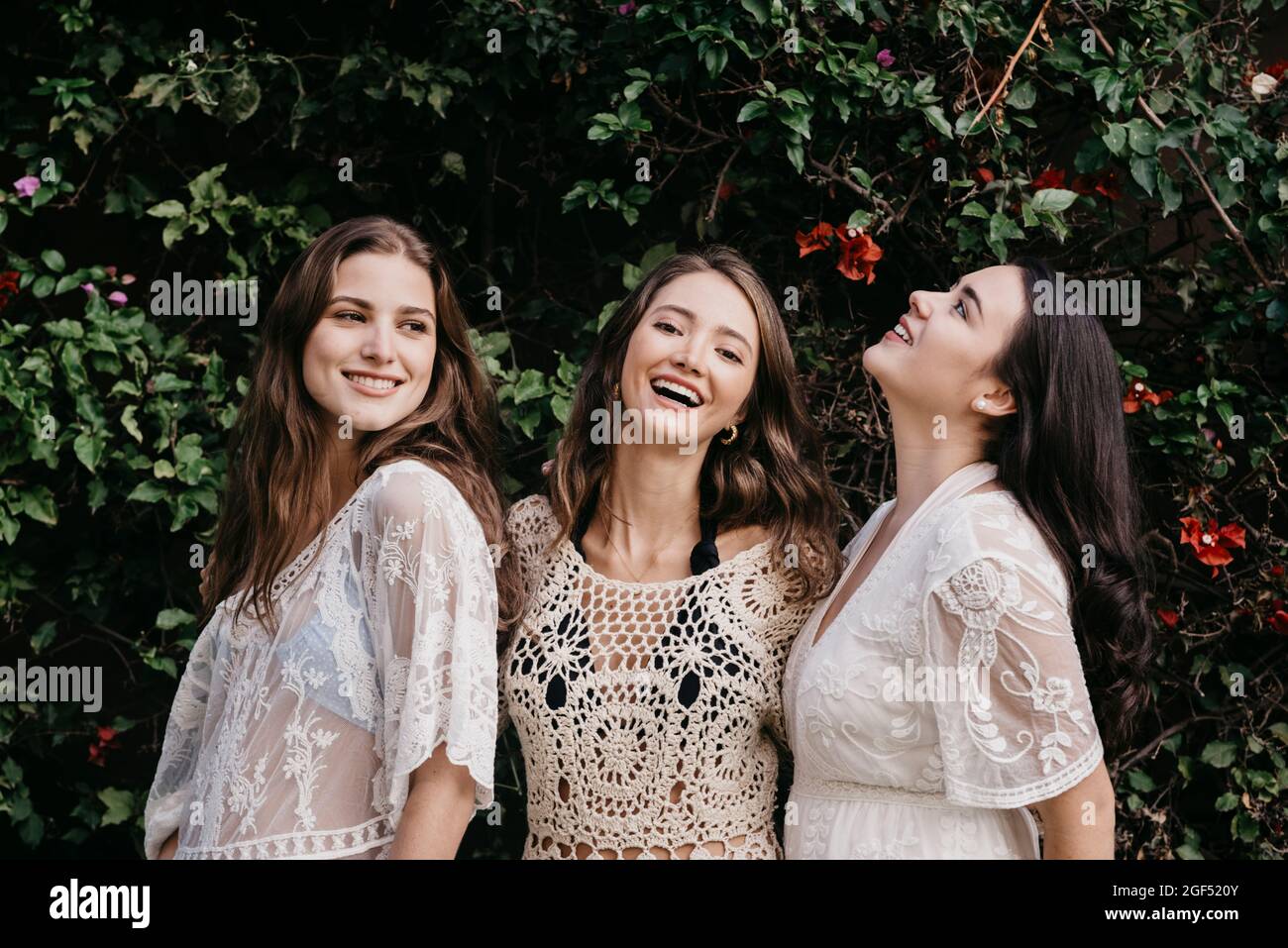 De jeunes femmes heureuses debout ensemble devant des plantes ivy Banque D'Images