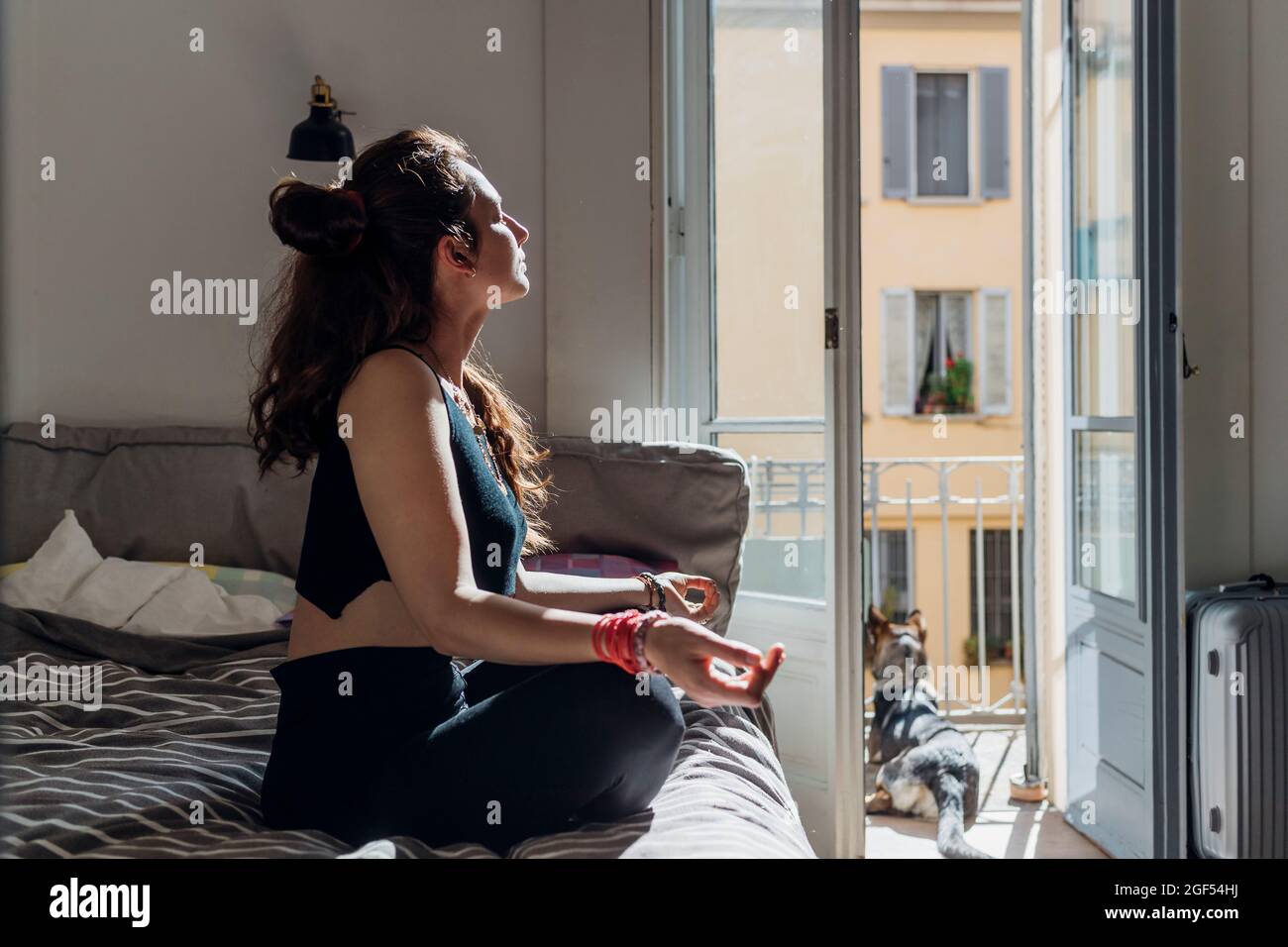 Femme méditant en pratiquant le yoga sur le lit dans l'appartement Banque D'Images