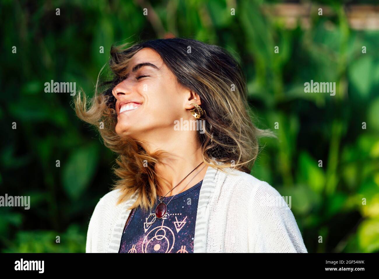 Bonne femme avec les yeux fermés tout en jetant les cheveux Banque D'Images