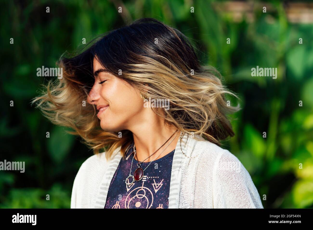 Jeune femme souriant tout en jetant les cheveux Banque D'Images