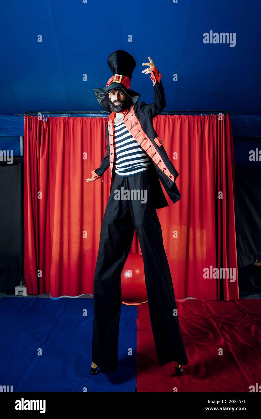 Un artiste masculin portant un costume de scène se présentant avec des pilotis dans un cirque Banque D'Images