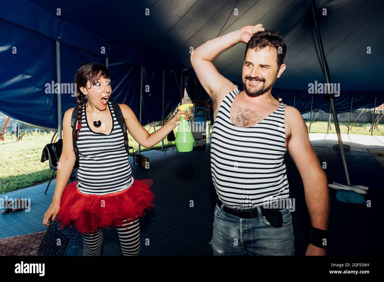 Une femme qui vaporise de l'eau sur un homme souriant dans les coulisses Banque D'Images