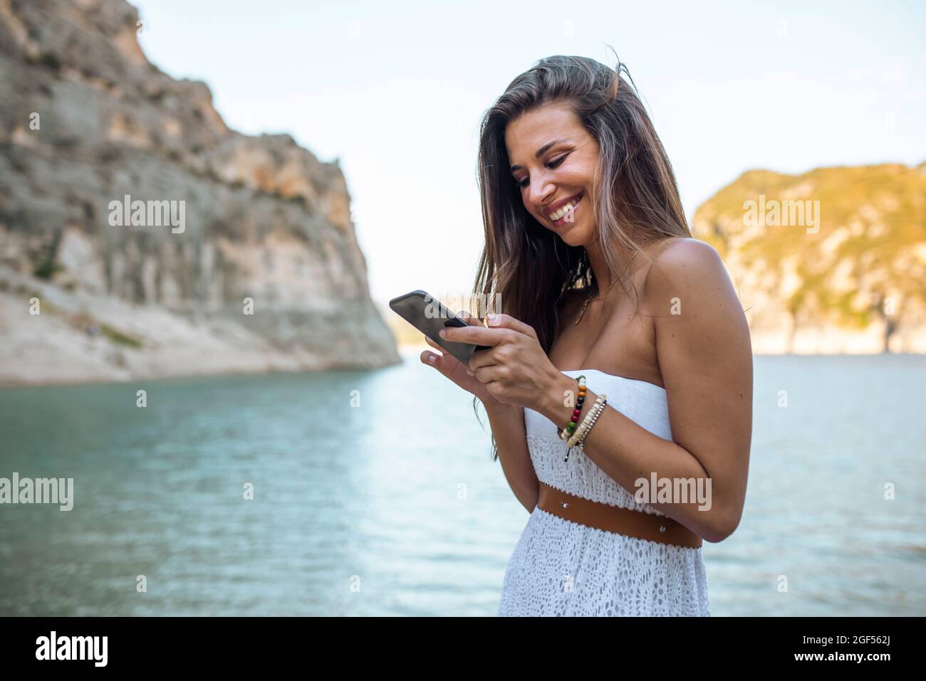 Femme souriante utilisant un smartphone à Pantano de Santa Ana, Castillonroy, Espagne Banque D'Images